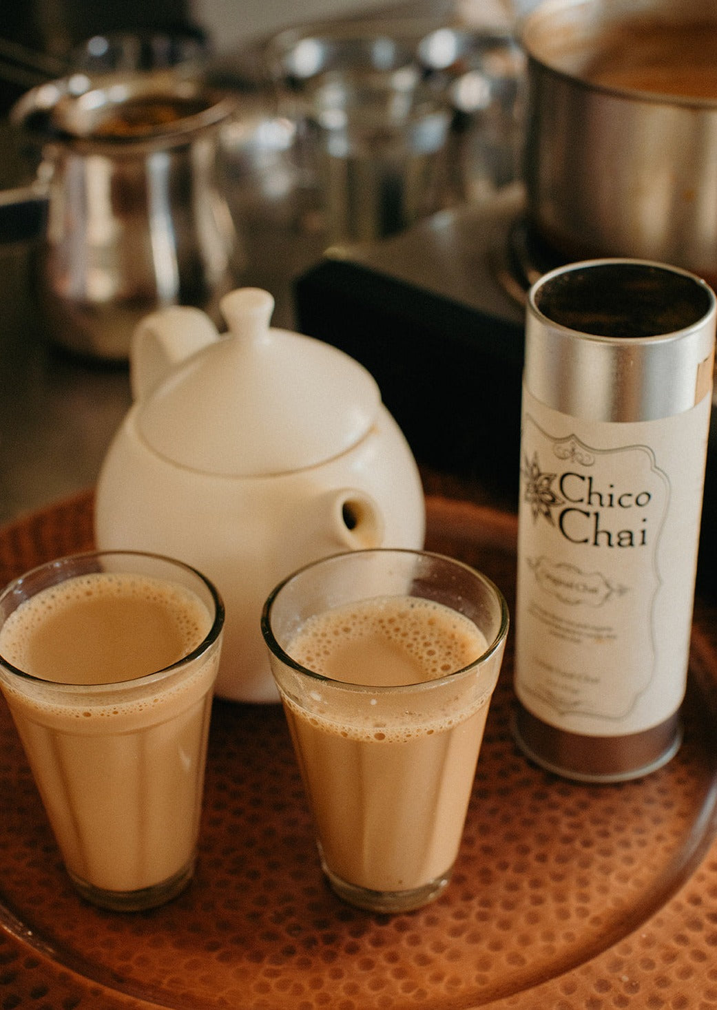 Indian chai in glass cups with metal kettle and other masalas to